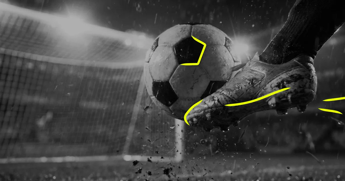 Black and white image of someone kicking a football into a goal in a stadium